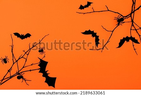 Halloween background. Black bats, spiders and branches on orange background flat lay with copy space.