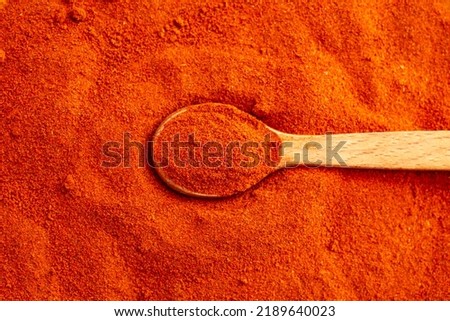 Paprika powder background, top view close up with a wooden tea spoon. 
