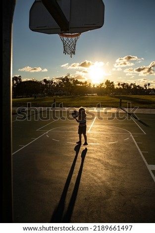 Cute little boy holding a basket ball trying make a score.