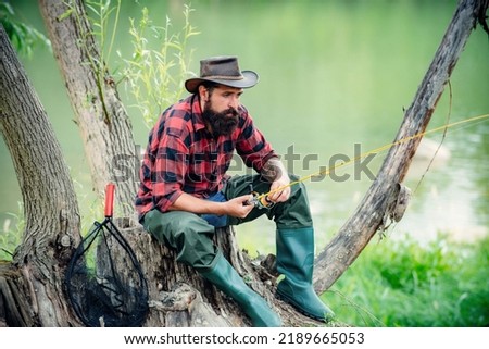 Man bearded fisher. Fishing on river. Active sunny day. Fishing as holiday. Activity and hobby. Having a good time. Catch me if you can. Good profit. Set up rod with hook line sinker. Hobby for soul. Royalty-Free Stock Photo #2189665053