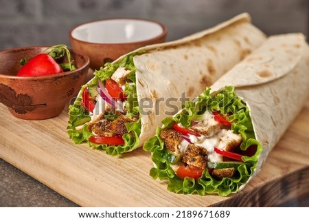 Two chicken wraps on wooden cutting board Royalty-Free Stock Photo #2189671689