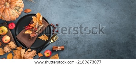 Autumn background with a plate with cutlery on a graphite background. Top view, copy space