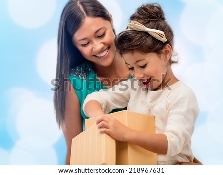 christmas, holidays, celebration, family and people concept - happy mother and child girl with gift box over blue lights background