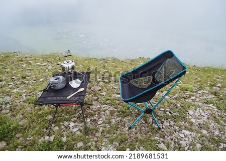 Picnic area high in the mountains, tourist furniture for camping in nature, compact folding chair, picnic set, fog in the forest. High quality photo
