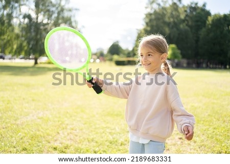Active preschool girl playing badminton in outdoor court in summer. Kid with racket. Royalty-Free Stock Photo #2189683331