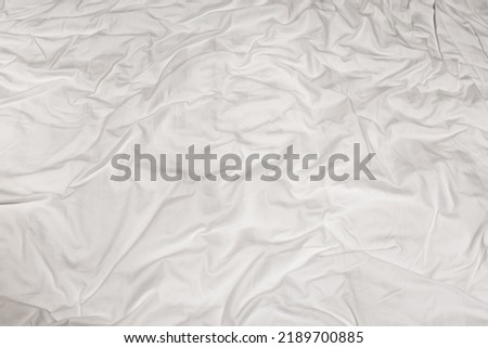 Close-up of the texture of a crumpled white sheet with tinted folded lines