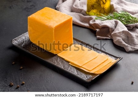cheddar cheese sliced on black plate on dark table Royalty-Free Stock Photo #2189717197