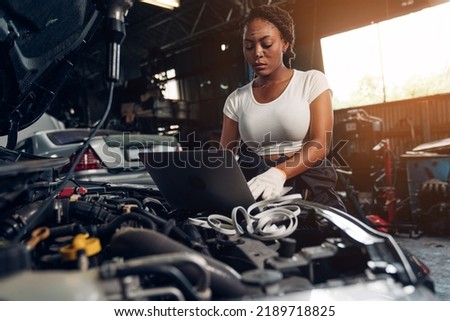 Woman auto mechanic using laptop for checking and repair maintenance auto engine is problems at car repair shop.