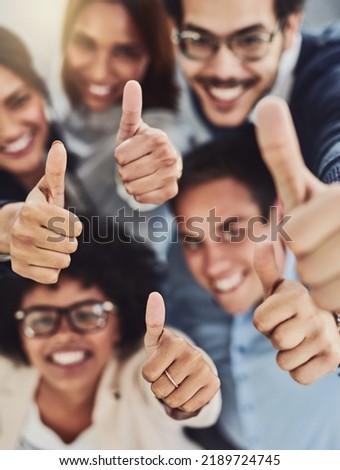 Thumbs up from a happy business team excited about the success they achieve together at work. Overhead view diverse group of corporate people excited by success and give approval to winning Royalty-Free Stock Photo #2189724745