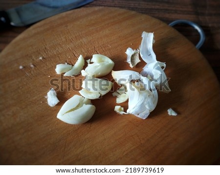 Peeled garlic placed on a chopping board in the kitchen. Potential benefits of adding garlic into daily meals.