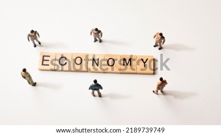Miniature figures businessman with shadow : meeting on economy word by wooden block words on white paper background, in concept of business and corporation