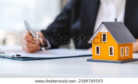 Real estate agent working sign agreement document contract for home loan insurance approving purchases for client with house model.