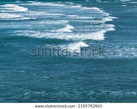 Beautiful foam on turquoise tidal waves. The surface of the water as a background. Blue ocean water