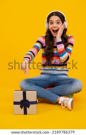 Amazed teenager. Teenager child holding gift box on yellow isolated background. Gift for kids birthday. Christmas or New Year present box. Excited teen girl.