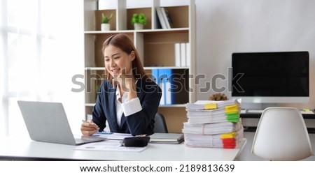 Happy beautiful Asian businesswoman working on laptop in office.