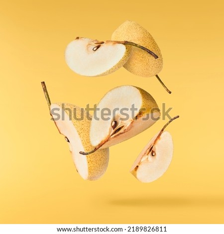 Fresh yellow ripe raw pear falling in the air isolated on yellow background. Food zero gravity conception. High resolution image.