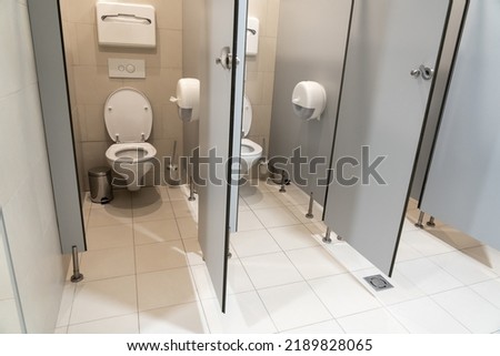 Pair of classic toilet cubicles with an open door in a public restroom Royalty-Free Stock Photo #2189828065