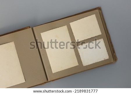 Clear blank photo frames to placed your pictures or text on old family album on grey background in retro style. Family traditions, memories and nostalgia concept. Antique album with old photos.