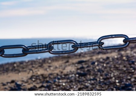 A closeup shot of a steel chain on the beach with bokeh background