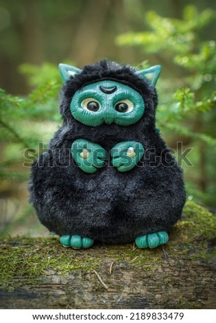The close-up view of a black fantasy creature toy with the moon sign on its head placed in the garden