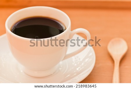 Cup of coffee on a wooden table in Vintage tone.