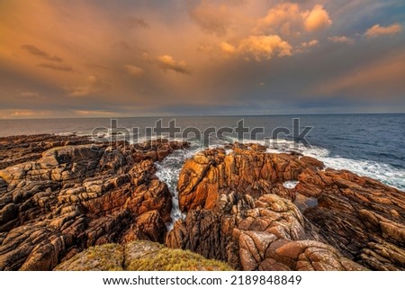 A scenic view of a beautiful seascape with rocks in a colorful sunset sky background in Ireland