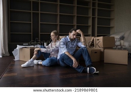 Exhausted couple sit rest on floor in living room near heap of cardboard boxes look unmotivated to unpack their stuff, feel tired. Financial problems, bank debt, hard relocation day, break up