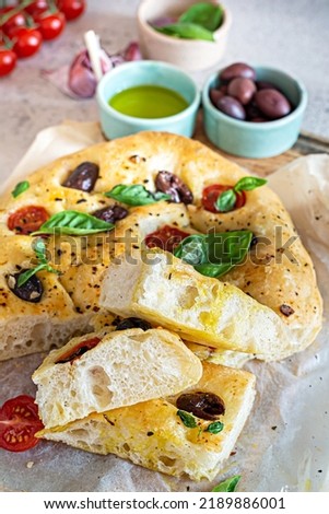 Fresh Italian flat bread Focaccia with tomatoes, olives, garlic and herbs on a light background. Royalty-Free Stock Photo #2189886001