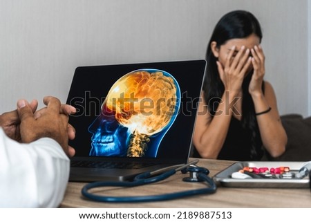Doctor showing a x-ray of pain in the brain on a laptop. Migraine Headache Royalty-Free Stock Photo #2189887513