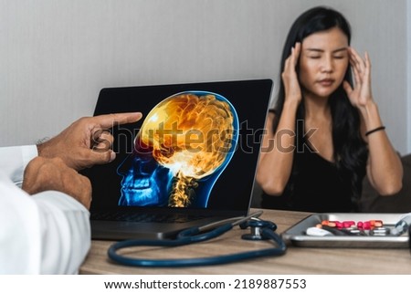 Doctor showing a x-ray of pain in the brain on a laptop. Migraine Headache Royalty-Free Stock Photo #2189887553