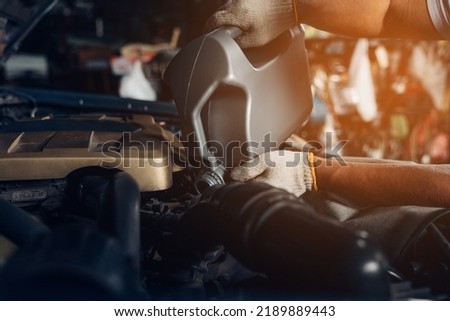 Auto mechanic are refueling and pouring oil quality into the engine motor car.