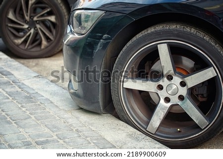 
Car wheel parked close to the curb on parking lot. 225.40r18 tire and bumper with scratch. Front side car parked close to the curb. Low clearance can cause bumper damage when parked close to the curb Royalty-Free Stock Photo #2189900609
