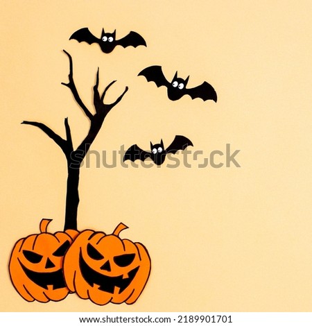 Halloween pumpkins with tree and bats on beige background. Creative copy space. Autumn holidays