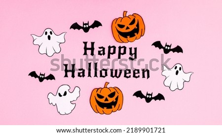 Pastel pink background with Happy Halloween text surrounded by creepy stickers. Flat lay Autumn holidays concept.