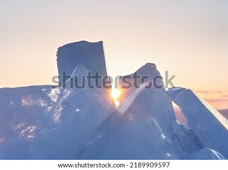Winter landscape with ice hummocks glittering in the sun and mountains of Lake Baikal in Siberia at sunset. Natural background.