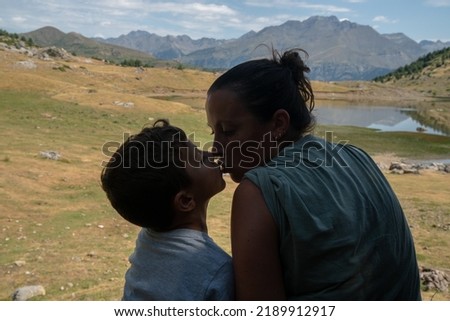 silhouette of a mother kissing her infant son on a nature background