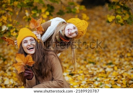Hello october. happy young mother and daughter in orange hats with autumn yellow leaves having fun time outside in the city park in autumn. Royalty-Free Stock Photo #2189920787