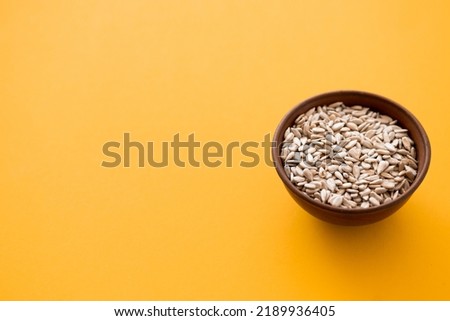 wooden bowl of sunflower seeds on yellow