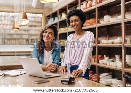 Successful young ceramists smiling at the camera while working in their store. Happy female entrepreneurs using a laptop together. Two young businesswomen running a creative small business. Royalty-Free Stock Photo #2189952665