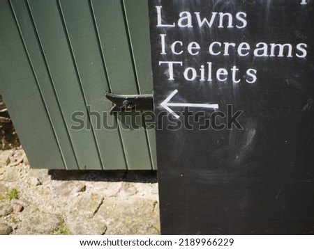 Chalk sign pointing to lawns, ice creams and toilets - important parts of a British historic attraction and concept of summer holiday