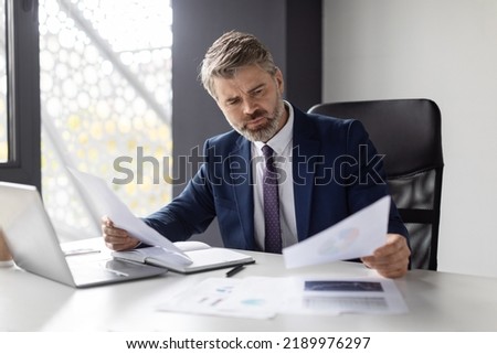 Thoughtful Mature Businessman Working With Papers At Desk In Modern Office, Busy Middle Aged Male Entrepreneur Wearing Suit Reading Financial Documents, Checking Company Annual Reports, Free Space Royalty-Free Stock Photo #2189976297