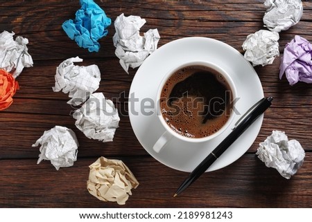 Cup of coffee and crumpled paper balls on wooden background, top view