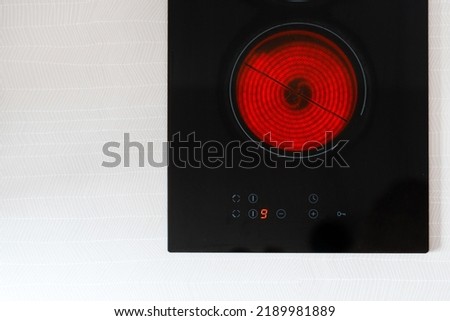 top view of glass ceramic hob with red hot burner and control panel with temperature button on countertop in kitchen Royalty-Free Stock Photo #2189981889