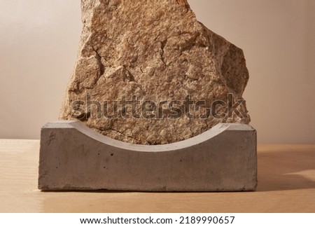 A podium made of concrete for the presentation of the product on a background of beige stone. The pedestal is made of natural natural material. Layout for exhibitions. High quality photo