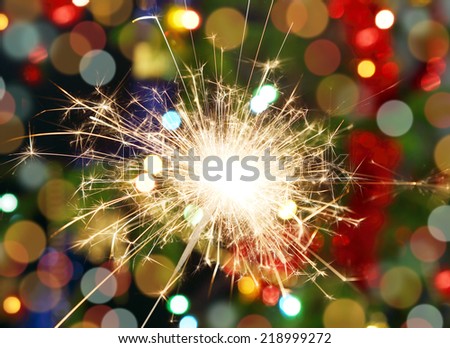sparkler burning on background decorated Christmas tree 