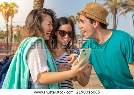Multicultural group of trendy young friends laughing looking the smartphone.