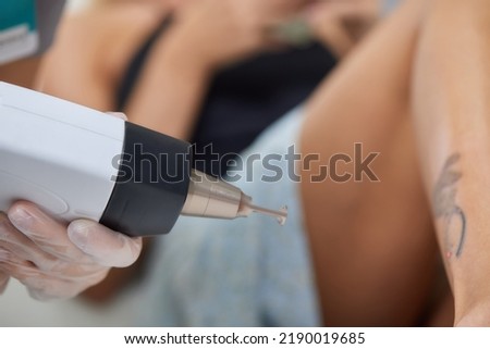 Young woman undergoing laser tattoo removal procedure in salon, closeup.