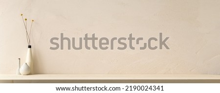 Decorative vase with branches at wooden table near bright wall. Royalty-Free Stock Photo #2190024341