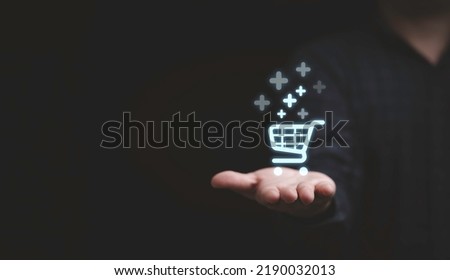 Businessman hand holding virtual trolley cart icons with plus sign symbol to add or receive order , Technology online shopping business concept.
