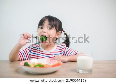 Cute asian child girl eating healthy vegetables and milk for her meal Royalty-Free Stock Photo #2190044169
